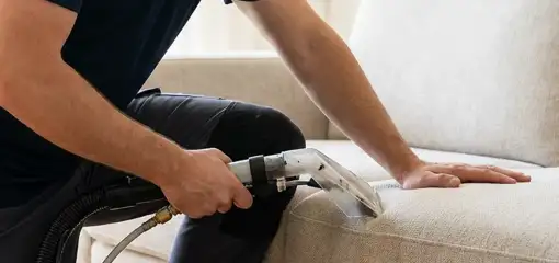 Professional upholstery cleaner deep-cleaning a fabric sofa with a handheld extraction tool, Pittsburgh, PA.
